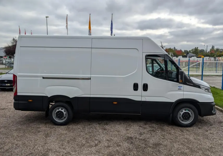 Vue de profil côté droit d’un utilitaire Iveco Daily blanc avec porte coulissante et bas de caisse noir.