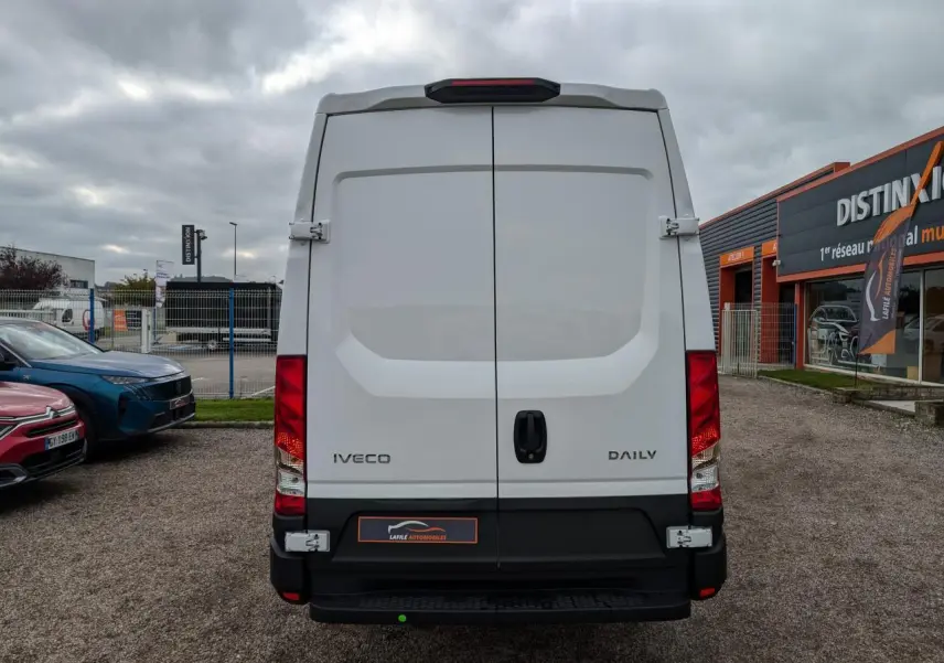Vue arrière d’un utilitaire Iveco Daily blanc avec portes battantes et feux arrière rouges visibles.