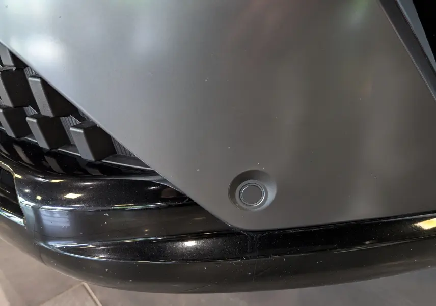 Détail du capteur de stationnement avant sur le pare-chocs noir du Renault Austral blanc nacré.