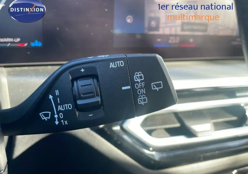 Gros plan sur la commande des essuie-glaces dans l’habitacle d’une BMW Série 3 Touring noire, avec tableau de bord flou en arrière-plan.