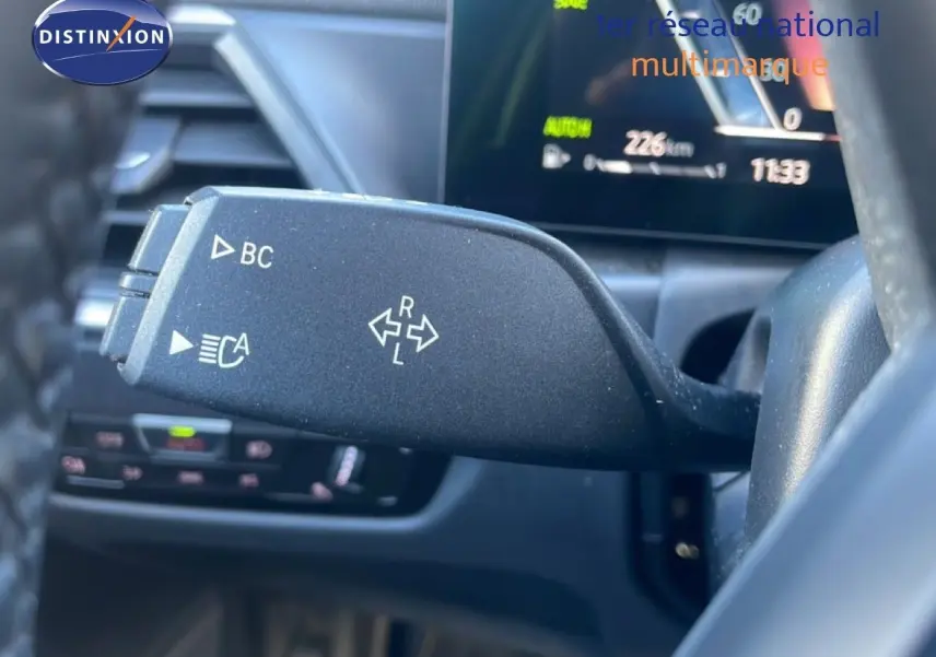 Gros plan sur la commande de clignotant noire à gauche du volant dans l’habitacle d’une BMW Série 3 Touring F31 noire.