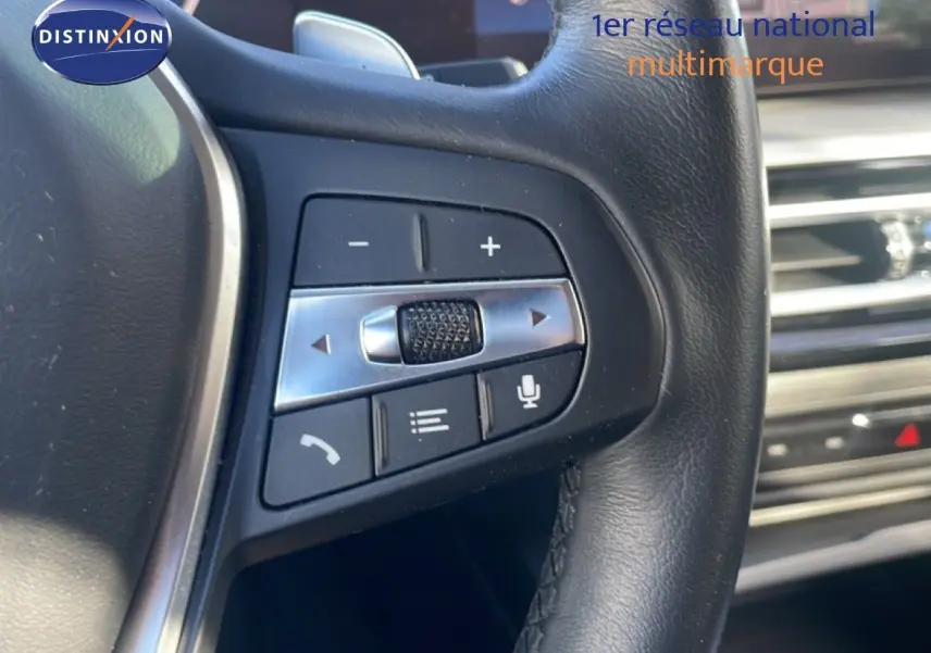 Gros plan sur les commandes du volant en cuir noir de la BMW Série 3 Touring F31 noir saphir, intérieur moderne.