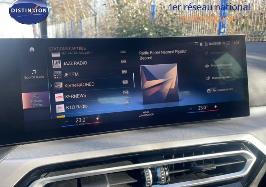 Écran tactile intérieur affichant la radio et la climatisation d'une BMW Série 3 Touring F31 noire, vue de face.