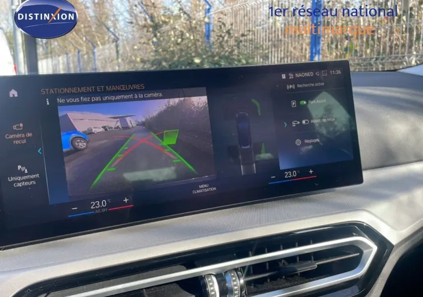 Écran central affichant la caméra de recul et l'assistance au stationnement dans une BMW Série 3 Touring noire, vue intérieure.