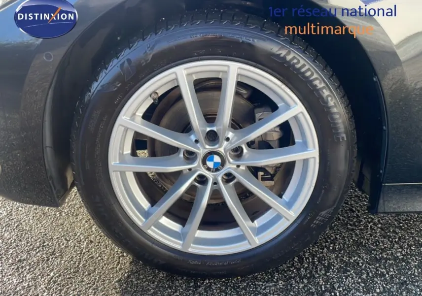Gros plan sur la roue avant droite d’une BMW Série 3 Touring noire, avec jante alliage argent et pneu Bridgestone.