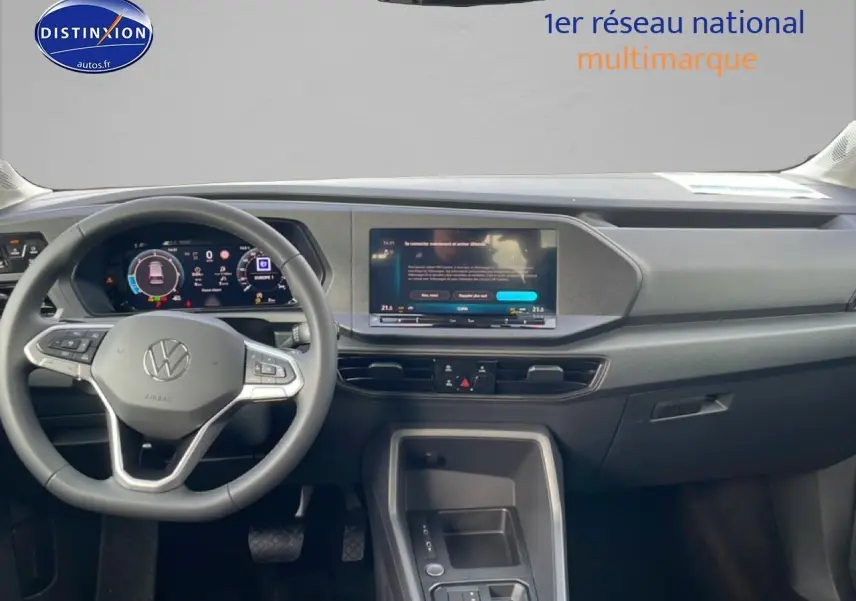 Vue intérieure avant du tableau de bord du Volkswagen Caddy 2025 avec écran tactile et volant multifonction gris.