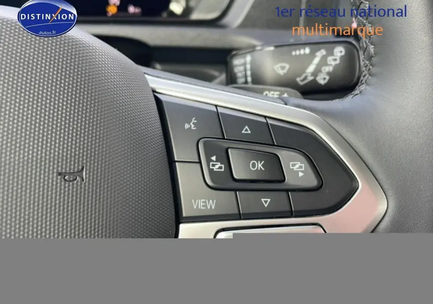 Gros plan sur les commandes au volant cuir multifonction du Volkswagen Caddy 2.0 TDI 122 DSG7, intérieur noir.