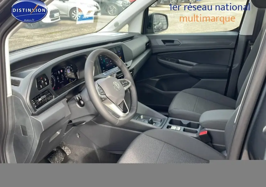 Vue intérieure côté conducteur du Volkswagen Caddy gris indien 2025, avec tableau de bord numérique et volant cuir multifonction.