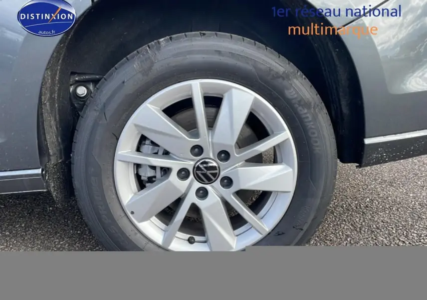 Gros plan sur la roue avant gauche du Volkswagen Caddy gris indien, mettant en valeur la jante alliage et le logo VW.