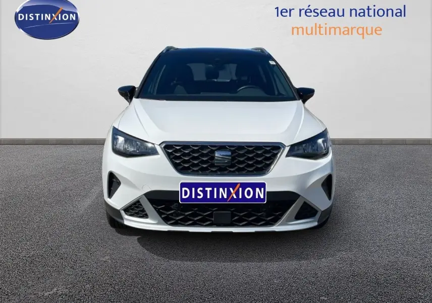 Vue frontale d'un SEAT Arona blanc Nevada avec toit noir, calandre noire et phares LED allumés.