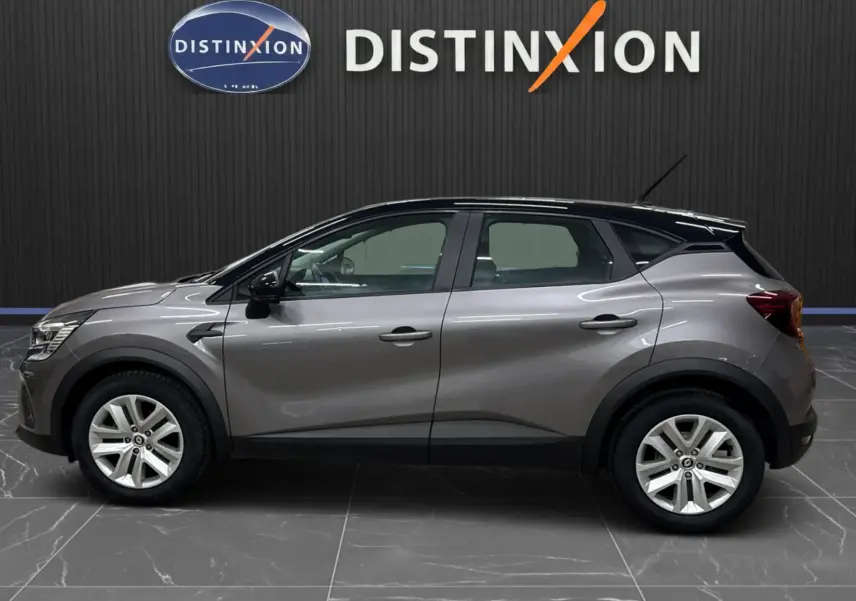 Profil droit d'un Renault Captur gris foncé avec toit noir, version TCE 90 CH BUSINESS BVM6, sur fond intérieur showroom.