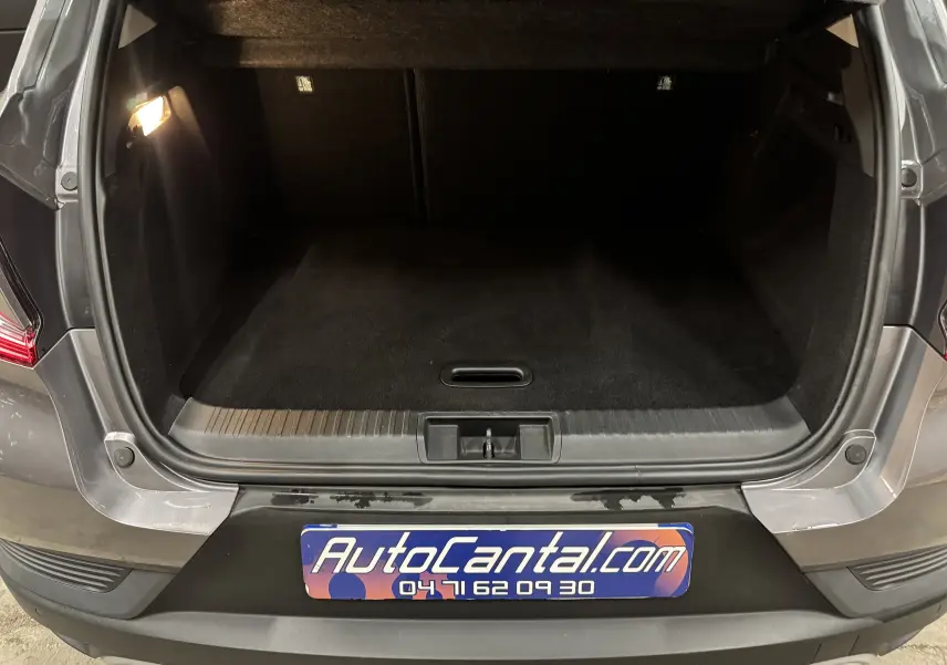 Coffre ouvert vu de l’arrière d’un Renault Captur gris foncé avec toit noir, montrant l’espace de chargement vide et éclairé.