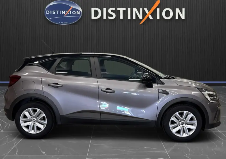 Renault Captur TCE 90 Business gris foncé avec toit noir, vue de profil côté gauche dans un showroom.