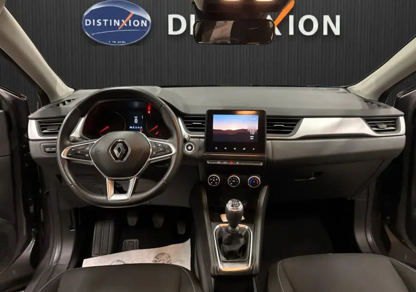 Vue intérieure frontale du tableau de bord et volant du Renault Captur TCE 90 Business, avec écran tactile et levier de vitesse manuel.