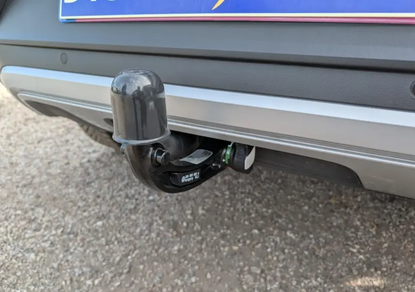 Gros plan sur l'attelage amovible noir fixé au pare-chocs arrière gris métallisé du Volkswagen T-Roc 2025.