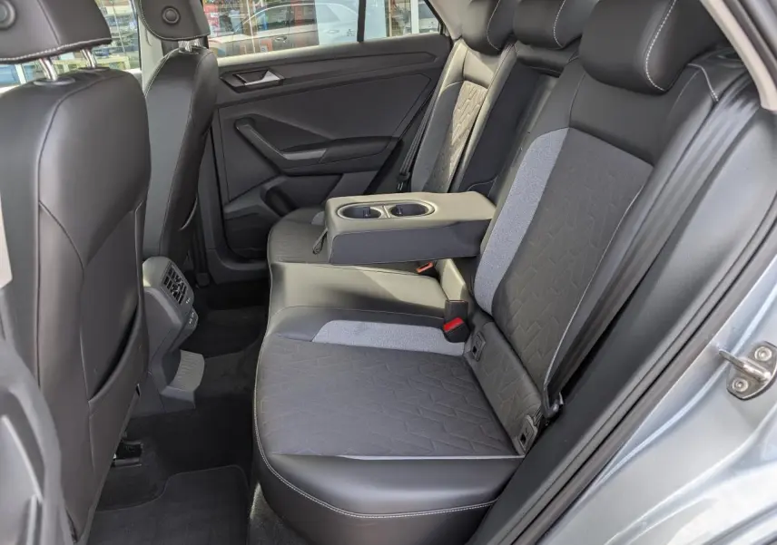 Vue côté droit de la banquette arrière gris foncé et tissu clair du Volkswagen T-Roc 2025 avec accoudoir central déployé.