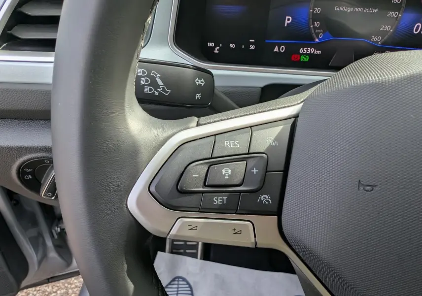Gros plan sur le volant côté gauche du Volkswagen T-Roc gris 2025, avec commandes du régulateur adaptatif visibles.