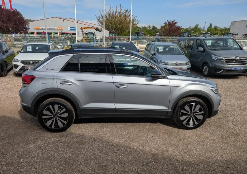 Profil droit d'un Volkswagen T-Roc gris métallisé avec jantes alliage 17 pouces et toit noir, stationné en extérieur.