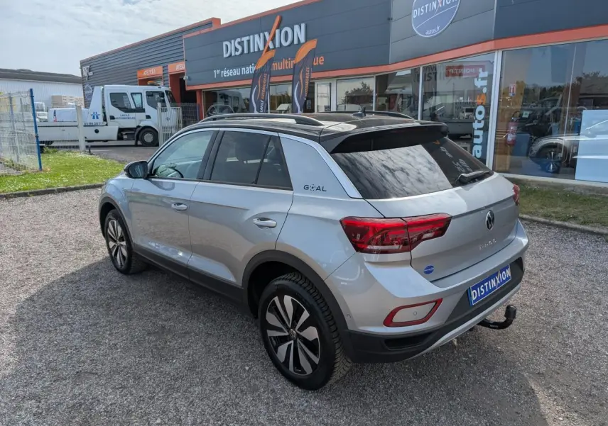 Volkswagen T-Roc gris vue 3/4 arrière droit avec toit noir et attelage amovible visible.