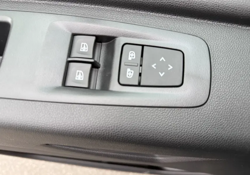 Gros plan sur les commandes de lève-vitres et réglage des rétroviseurs côté conducteur du Renault Master noir nacré 2024.
