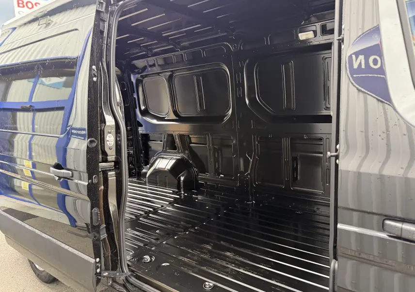 Vue latérale gauche du Renault Master noir nacré 2024 avec porte coulissante ouverte montrant l'intérieur vide du coffre.