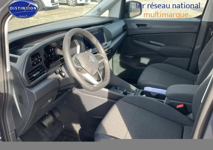 Intérieur avant droit du Volkswagen Caddy 2025 gris pur, volant cuir multifonction et sièges tissu noir titane.