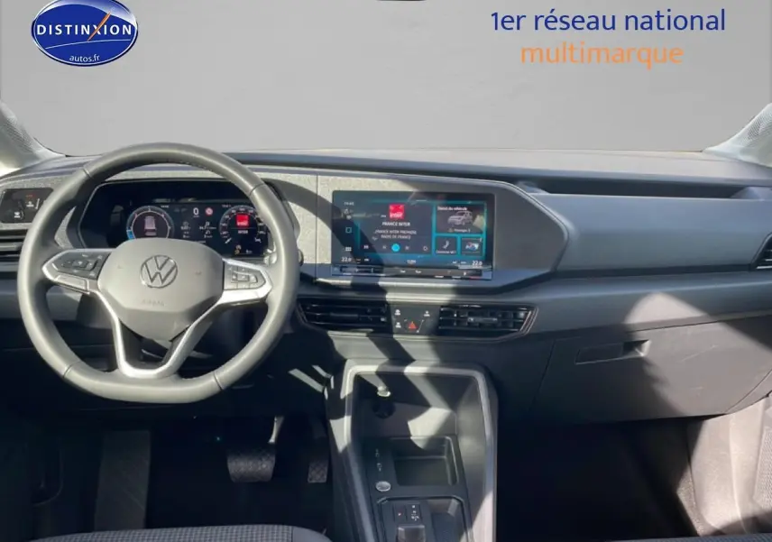 Vue intérieure du tableau de bord du Volkswagen Caddy gris pur 2025, avec volant cuir multifonction et écran tactile central.