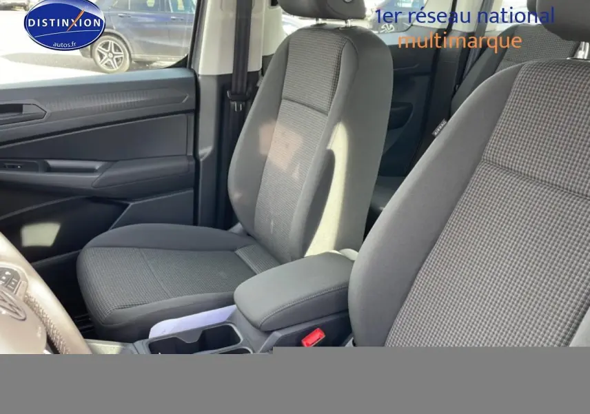 Vue intérieure côté conducteur du Volkswagen Caddy 2025 gris pur, sièges tissu noir titane avec accoudoirs réglables.