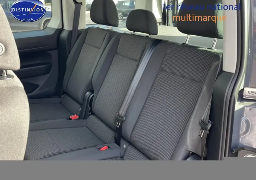 Vue intérieure côté droit sur la banquette arrière en tissu noir à motif double grid du Volkswagen Caddy gris pur 2025.