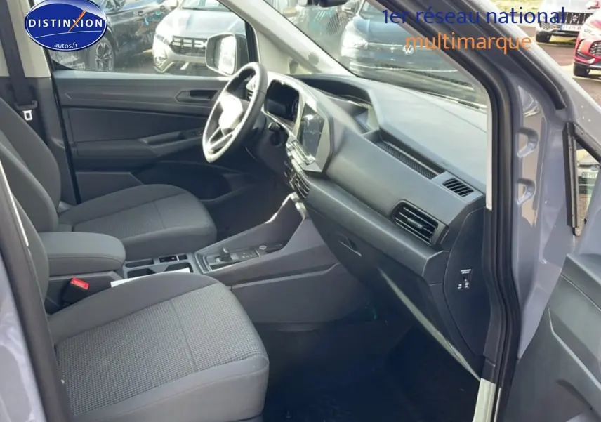 Intérieur avant droit du Volkswagen Caddy gris pur 2025, sièges tissu noir titane et tableau de bord moderne.