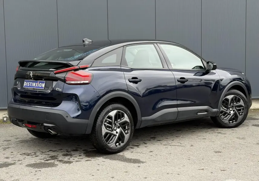 Vue 3/4 arrière droite d'une Citroën C4 2024 bleu Eclipse avec toit noir et jantes alliage 18 pouces.