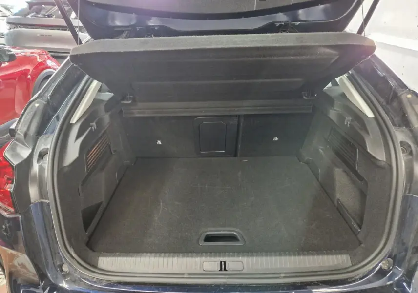 Vue intérieure côté gauche des sièges avant gris et noir avec accoudoir central et volant de la Citroën C4 2024.