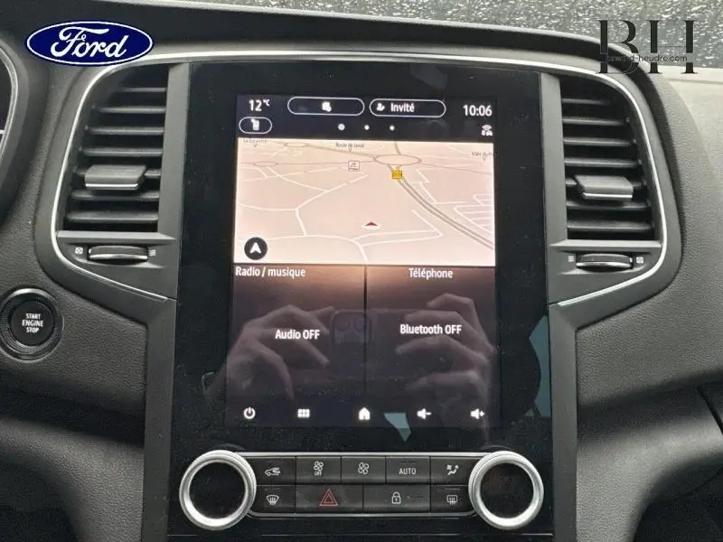 Écran tactile central avec navigation et commandes clim dans l'habitacle d'une Renault Mégane blanche, vue de face.