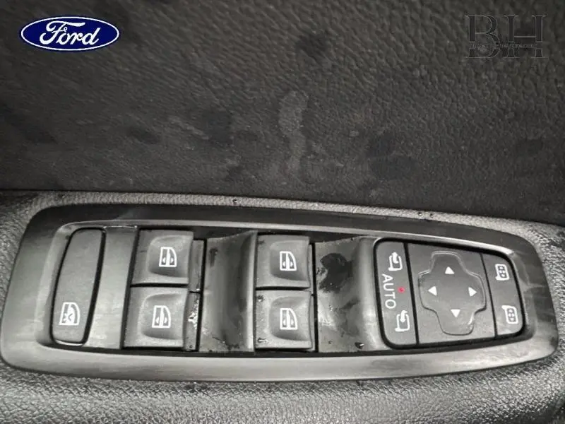Panneau de commandes des vitres et rétroviseurs électriques sur porte avant gauche d’une Renault Mégane blanche.