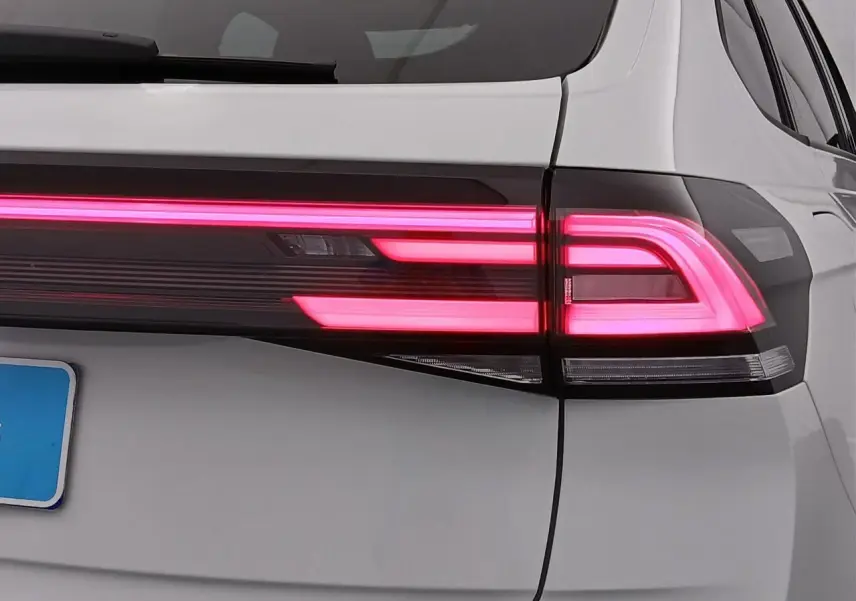 Gros plan sur le feu arrière droit allumé du Volkswagen Taigo blanc pur avec toit noir, version R-Line 2025.