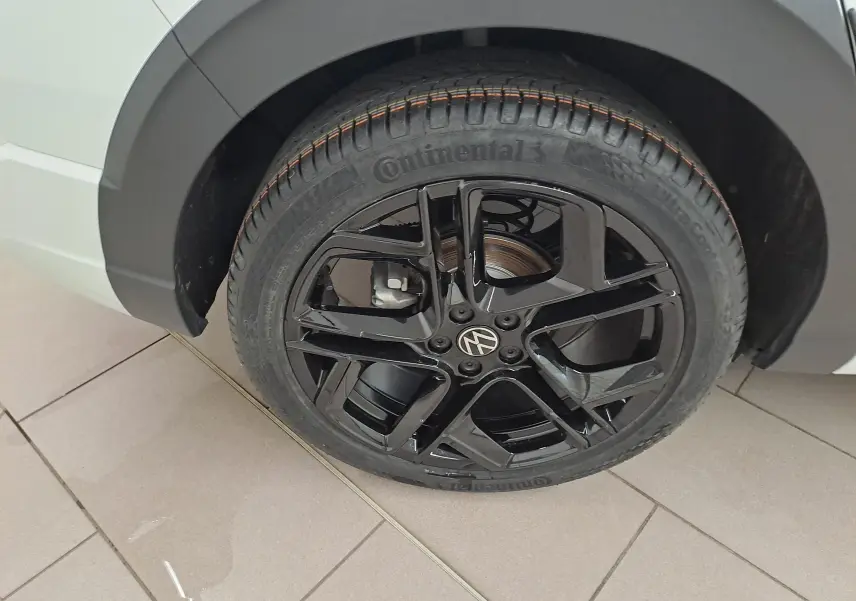 Gros plan sur la roue arrière droite du Volkswagen Taigo blanc pur, jante alliage noir brillant R-Line Edition.
