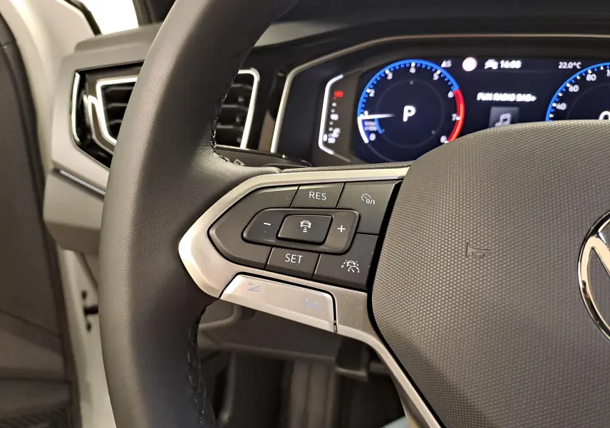 Gros plan sur le volant multifonctions noir de la Volkswagen Taigo 2025 avec tableau de bord digital en arrière-plan.