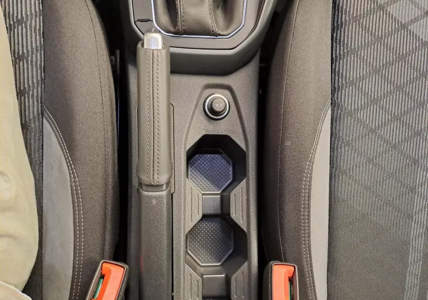 Vue plongeante sur la console centrale noire entre les sièges avant gris foncé du Volkswagen Taigo 2025.