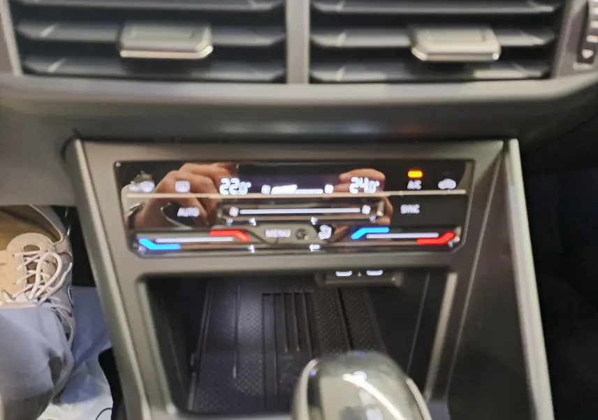 Gros plan sur la console centrale du Volkswagen Taigo 2025, avec commandes tactiles de climatisation bi-zone et levier de vitesse noir.