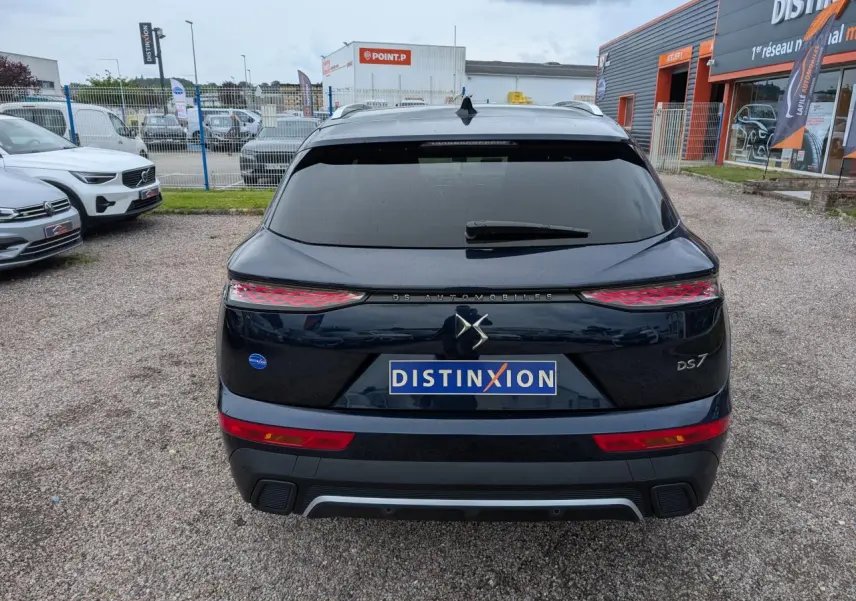 Vue arrière d'un DS7 bleu métallisé avec feux arrière 3D et logo DS Automobiles sur un parking extérieur.