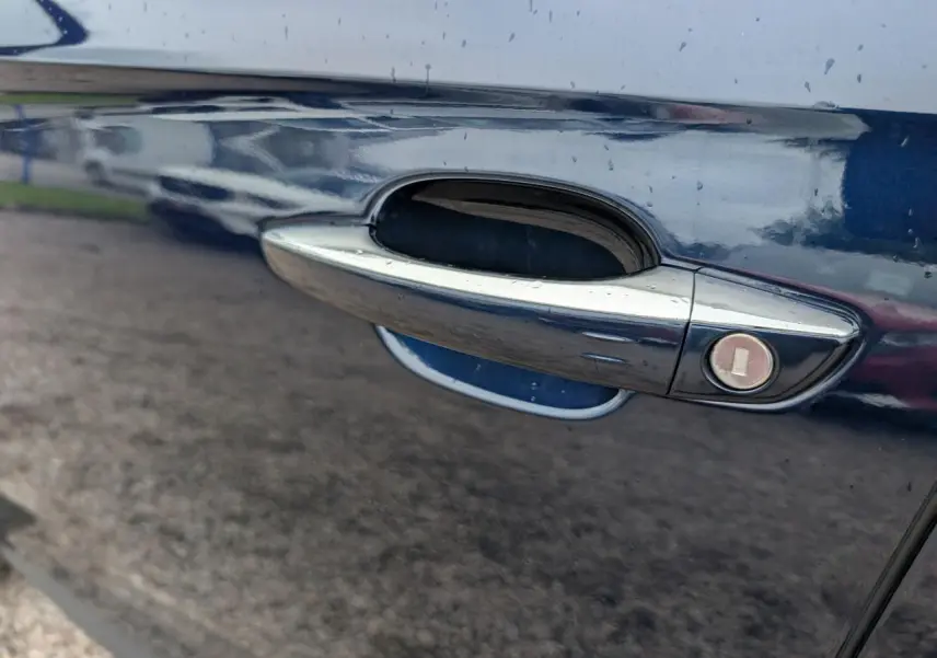 Poignée de porte chromée sur la portière côté gauche d’un DS7 bleu métallisé 2024, avec serrure intégrée.
