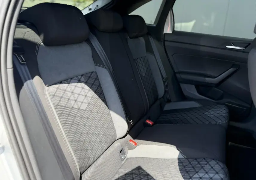 Vue intérieure de la banquette arrière du Volkswagen Taigo TSI 116 DSG R-Line, sellerie tissu noir et gris à motifs géométriques.