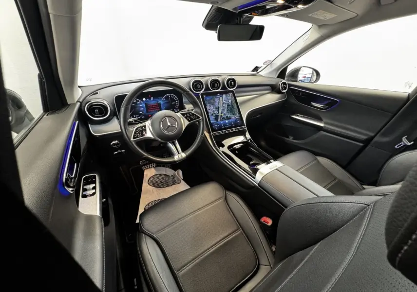 Vue intérieure avant droite du Mercedes GLC 300 E Business Line 2023, sièges cuir noirs et écran tactile central lumineux.