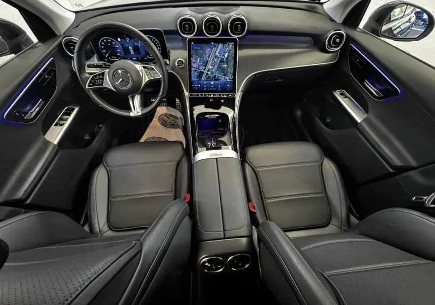 Intérieur Mercedes GLC 300 E 2023 vu de dessus, sièges cuir noirs et écran tactile central vertical lumineux.