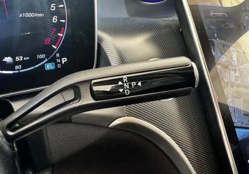 Gros plan sur la commande de boîte automatique noire dans l’habitacle du Mercedes GLC gris foncé, avec tableau de bord numérique visible.