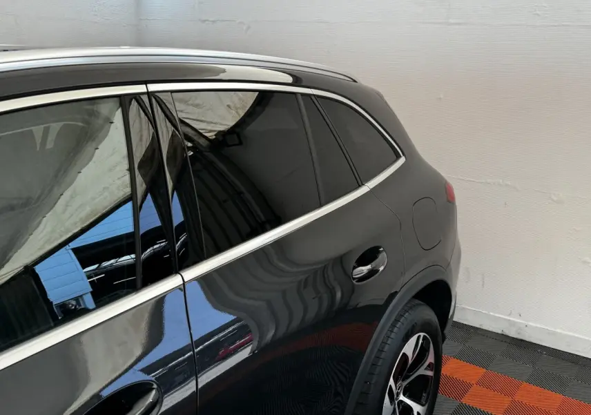 Vue latérale arrière droite d'un Mercedes GLC 300 E Business Line 4MATIC gris foncé avec jante alliage et vitres teintées.