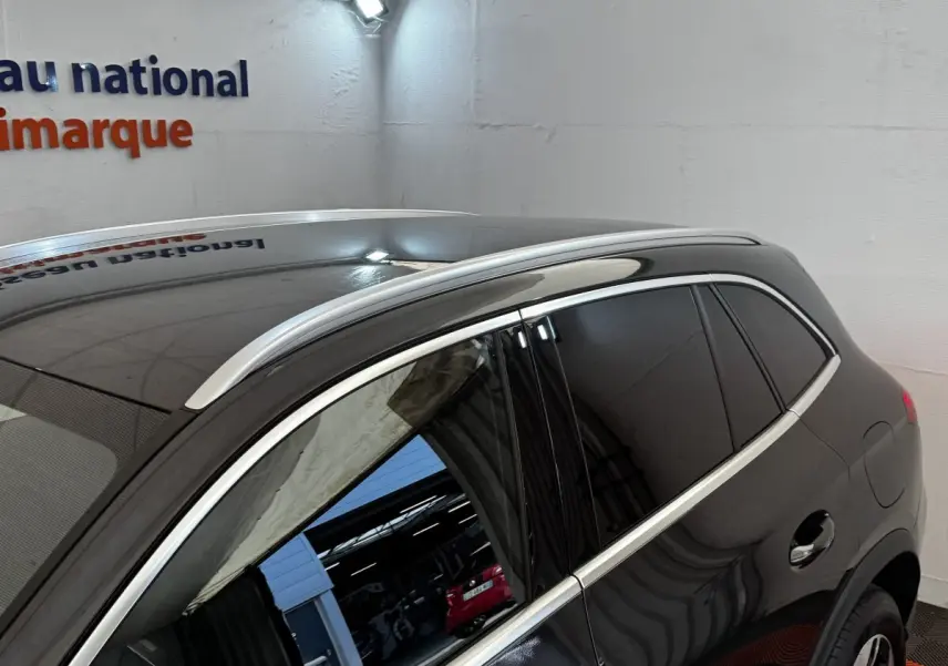 Vue latérale droite d’un Mercedes GLC 300 E Business Line gris foncé avec vitres teintées et barres de toit chromées.