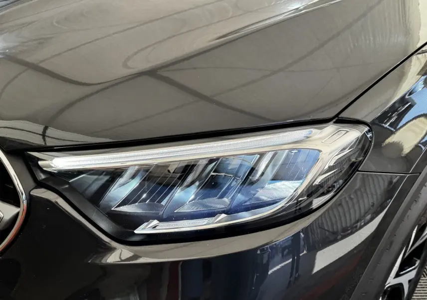 Gros plan sur le phare avant droit du Mercedes GLC 300 E Business Line gris foncé, avec détails LED visibles.