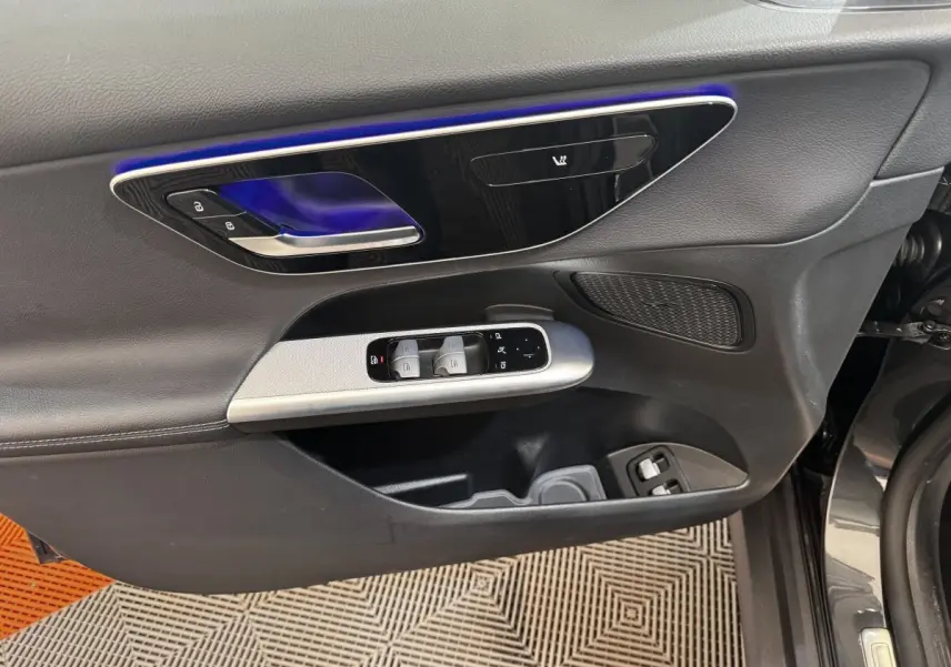 Vue rapprochée de la porte avant gauche du Mercedes GLC gris foncé avec commandes de vitres et éclairage d’ambiance bleu.