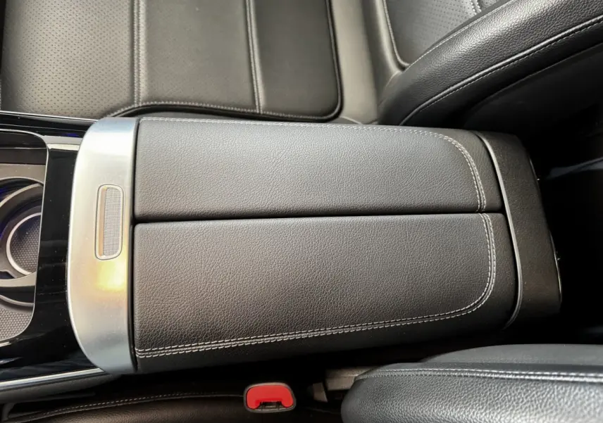 Vue rapprochée de l'accoudoir central en cuir noir avec surpiqûres blanches dans un Mercedes GLC 300 e Business Line 2023.